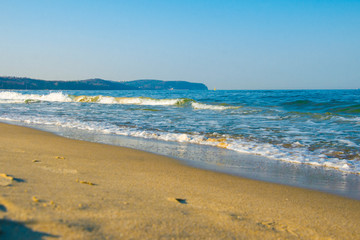 Fototapeta na wymiar Sea, sandy beach and rocky shore on the horizon.