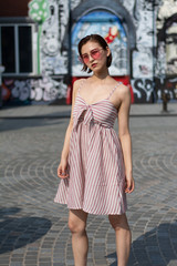 Asian Chinese model girl influencer street shot. Wearing pink dress and red shoes. Street Graffiti background.