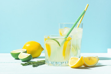 A drink of lemon and lime lemonade in transparent glasses a blue background bright sunlight. Summer...