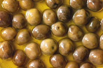 Food background green whole olives in olive oil. Close up