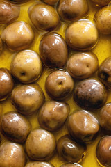 Food background green whole olives in olive oil. Close up