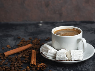 white Cup of Italian coffee with white marshmallow on dark table with copyspace