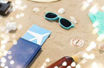 vacation, travel and tourism concept - air tickets in passport, vintage camera and hat and sunglasses on beach sand