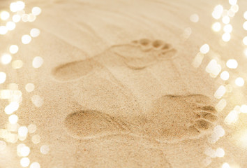 summer vacation concept - footprints in sand on beach
