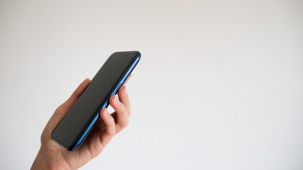 Side view of left female hand holding blank screen smartphone isolated on white background.
