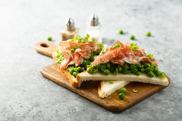 Healthy toasts with pea mash and prosciutto