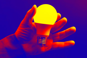 human hand holding the included led lamp on a dark background