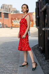 Asian Chinese model girl influencer street shot. Wearing red floral printed dress.  Street view background.