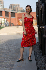 Asian Chinese model girl influencer street shot. Wearing red floral printed dress.  Street view background.