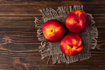 Three peaches on dark wooden background. Top view.