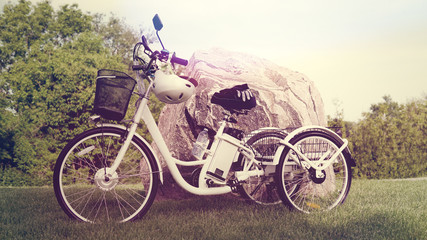 Electric trike or e bicycle in the park in sunny summer day. Shot from the side. A lot of ...