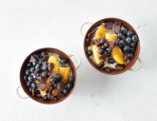 Breakfast table with plate oatmeal with fried banana, chocolate and blueberry on a white background...