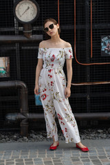 Asian Chinese model girl influencer street shot. Wearing white printed floral patterned jumpsuit.  Street view background.