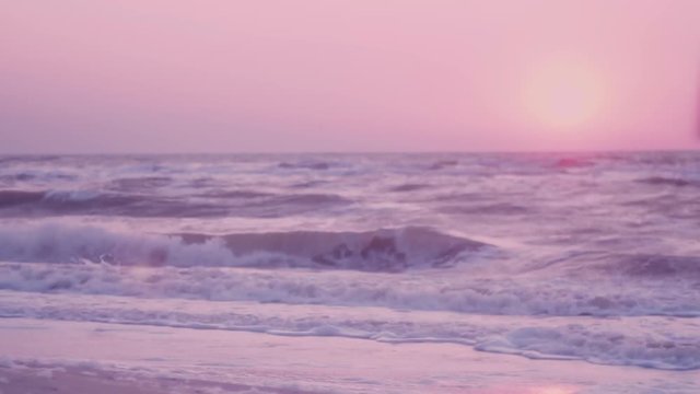 surf of the waves, foam on the background of a pink dawn, the sun