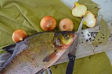 Freshly caught bream on a wooden Board and onions with spices.
