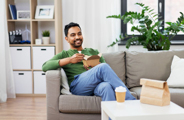 consumption and people concept - smiling indian man eating takeaway food at home