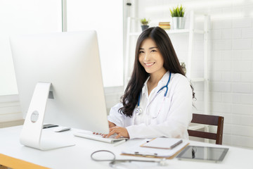 Obraz na płótnie Canvas Asian female doctor work at hospital office desk giving patient convenience online service advice, smiling write a prescription order medical with smartphone, health care, preventing disease concept.