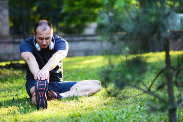 Young men training at the park.Handsome man do stretching exercises at autumn park.
