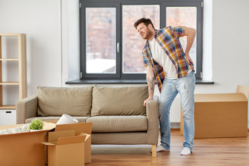 Fototapeta premium moving, people and real estate concept - man with sofa at new home suffering from back ache