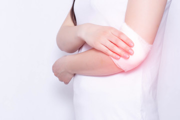 Medical compress on the elbow of the girl for pain and inflammation, white background, copy space,...