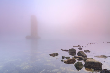 Pillar of a storm surge barrier in fog during sunset