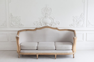 Luxurious bright Rococo interior with a large sofa and stucco on the walls. Selective focus.