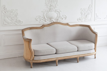 Luxurious bright Rococo interior with a large sofa and stucco on the walls. Selective focus.