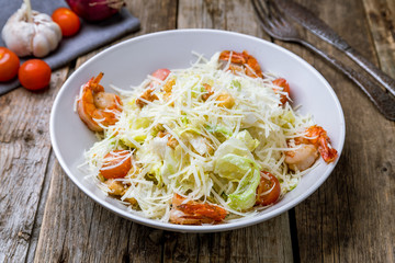 salad caesar with shrimps on wooden background