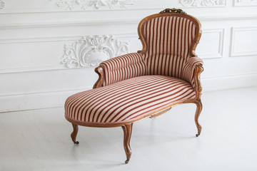 Vintage sofa with wood carvings in a luxurious light interior with stucco on the walls. Selective focus.