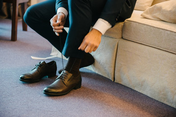 A man in a suit puts shoes on his feet.