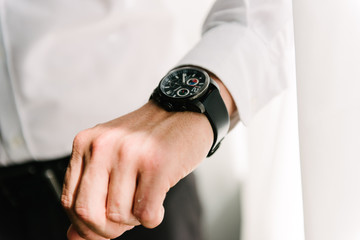 Man in suit with hand adjusts sleeve of shirt close-up