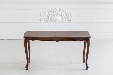 Vintage coffee table in the Rococo style with wood carvings in a luxurious interior with stucco. Selective focus.