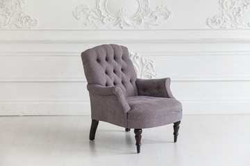 Living room in the Rococo style. Vintage grey armchair against the wall with plaster stucco...