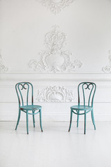 Vintage viennese chairs against the wall with a bas-relief of plaster stucco. Selective focus.
