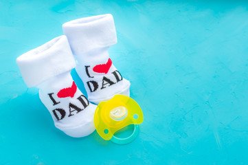 Socks with the words I love dad for a new baby and a yellow nipple on a blue background. Newborn baby concept