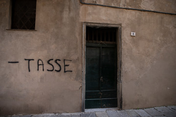 writing on a wall asking for less taxes. Albenga, Italy