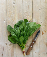 Fresh harvested organic spinach on a dark wooden table. Green vegetables with water drops....