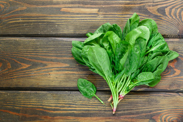 Fresh harvested organic spinach on a dark wooden table. Green vegetables with water drops....