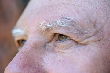 Closeup eye of caucasian old man. Portrait of old man outdoors. Caucasian male face background, close up eyes, macro