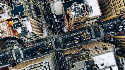 Luftaufnahme der Gebäudedächer der Innenstadt von New York. Vogelperspektive vom Helikopter auf die Infrastruktur der Stadtmetropole, Verkehrsautos, gelbe Taxis, die sich auf den Straßen der Stadt bewegen und die Alleen des Bezirks überqueren © BullRun
