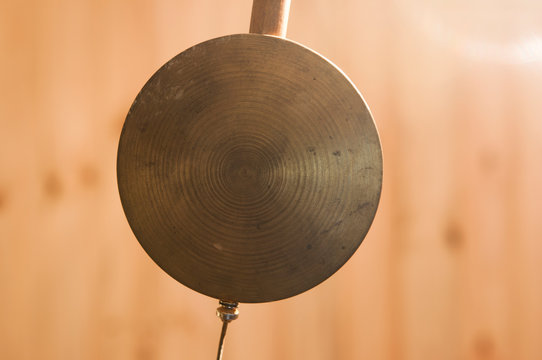 antique clock pendulum over wooden background