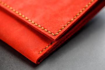 Red leather wallet on a dark background top view. Close-up, purse details, rivet and firmware