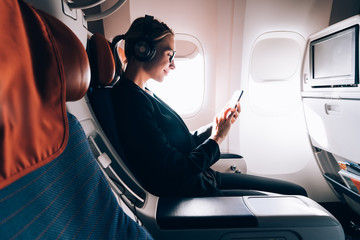 Side view of woman in formal wear watching online positive video while using wireless internet...