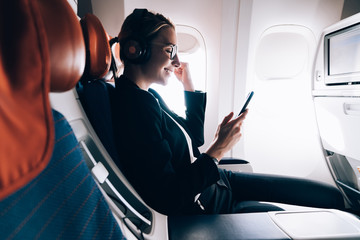 Excited young woman in headphones for noise cancellation overjoyed with news and celebrating...