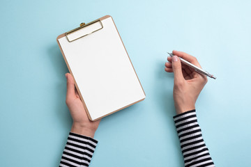 The woman holding  paper and pen on blue background. Copy space