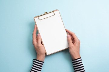 The woman holding  paper on blue background. Copy space