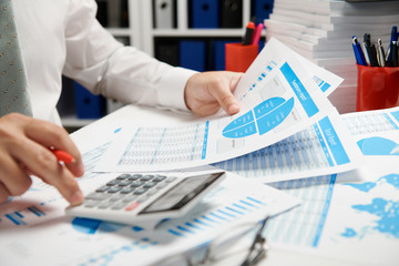 Businessman working and calculating, reads and writes reports. Office employee, table closeup....