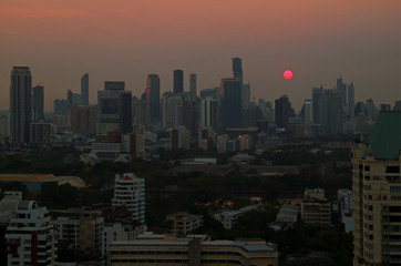 Panoramic view of the sun setting over skyscrapers in Bangkok downtown, Thailand