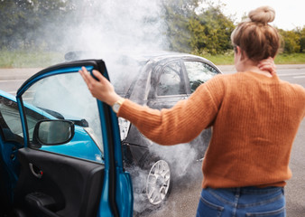 Rear View Of Female Motorist With Head Injury Getting Out Of Car After Crash