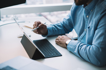 Concentrated businessman using tablet with stylus